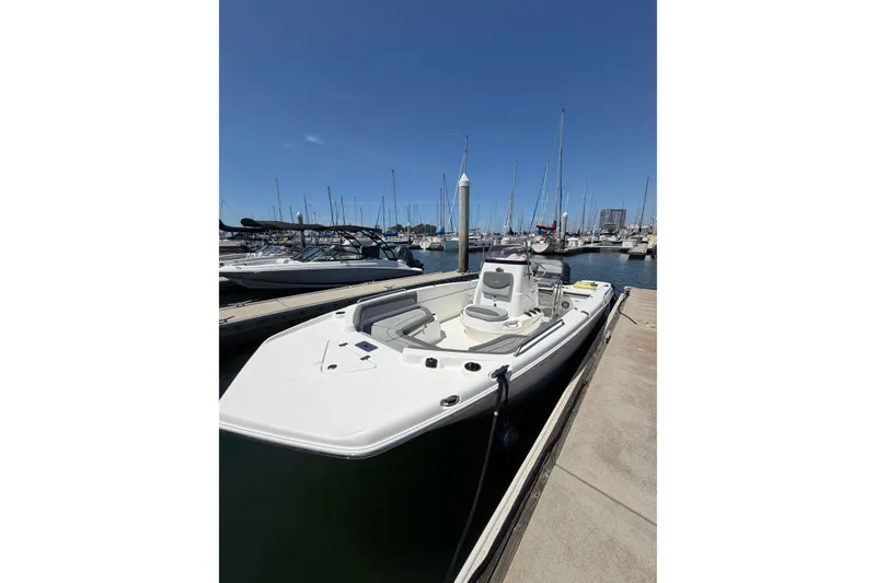 Slide: The Image of 2023 NauticStar 211 Hybrid boat docked at a marina under clear blue skies. - 2