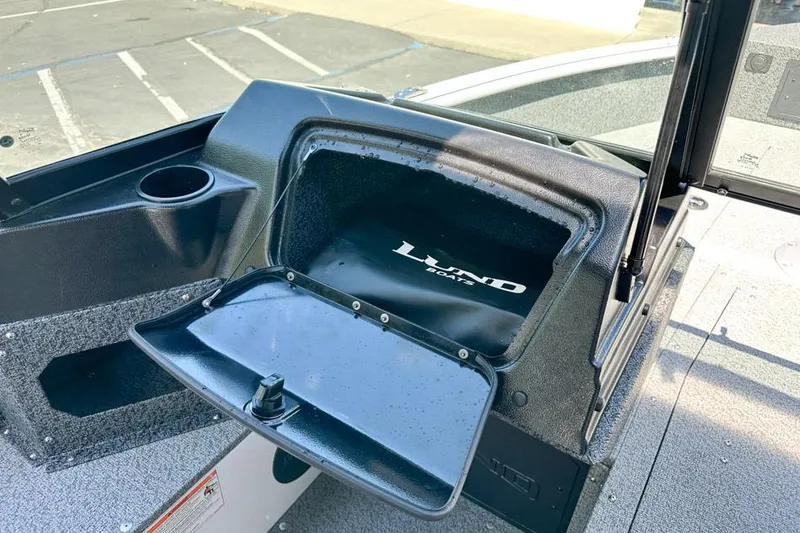 Slide: The Image of Open storage compartment on 2026 Lund 1700 Explorer Sport boat, featuring cup holder and logo. - 14