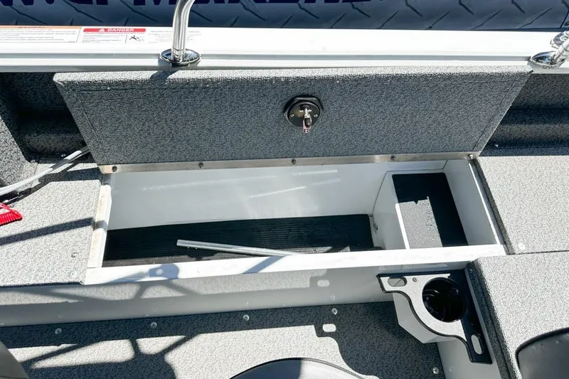 Slide: The Image of Open storage compartment in 2026 Lund 1700 Explorer Sport boat, featuring gray interior and cup holder. - 22