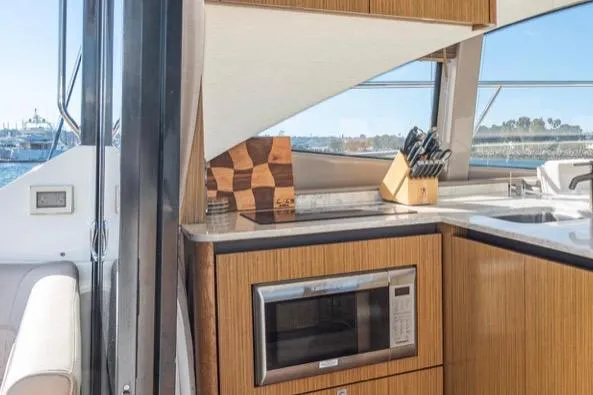 Slide: The Image of Modern galley/ starboard interior of 2017 Sea Ray 460 Sundancer yacht with split appliances microwave and prep  area  port and  fridge/freeze/cooktop stbd. - 12