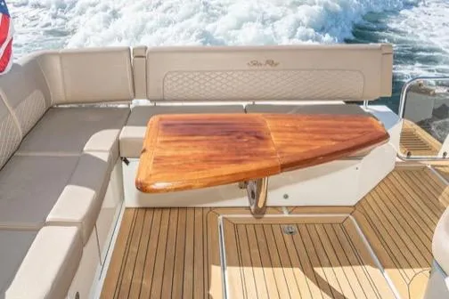 Slide: The Image of 2017 Sea Ray 460 Sundancer yacht with elegant wooden table and cushioned seating. - 6