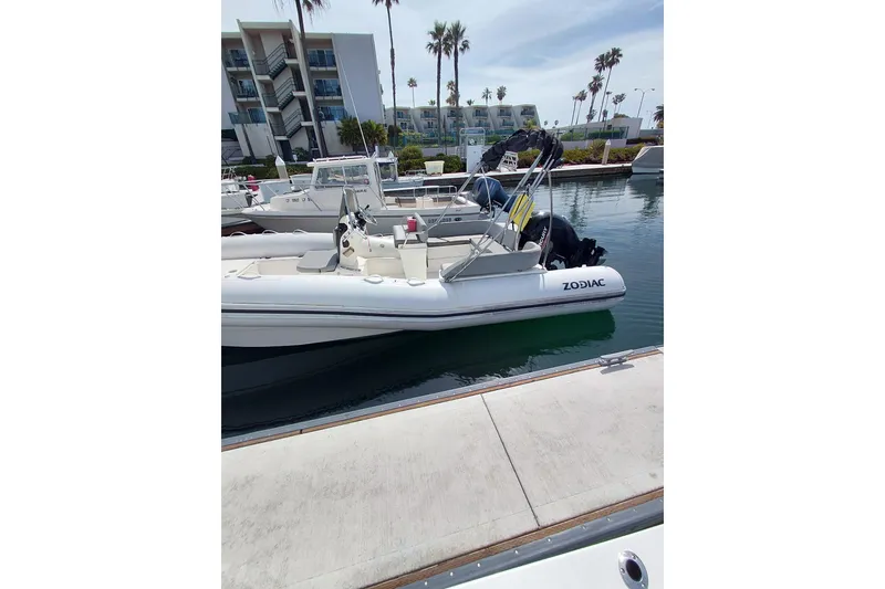 Slide: The Image of 2021 Zodiac N-ZO 680 boat docked in a marina with modern buildings in the background. - 2