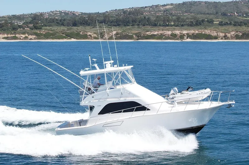 The Image of 2006 Cabo 40 Flybridge yacht cruising on open water with scenic coastline backdrop. - 0