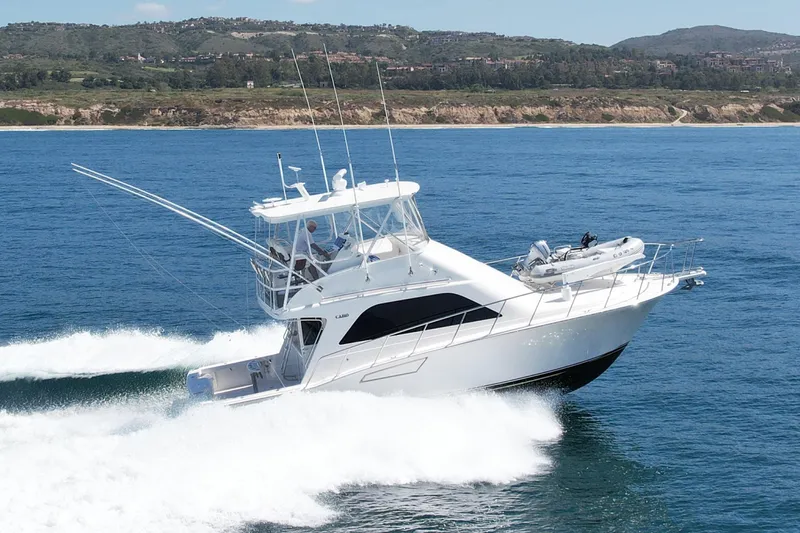 Slide: The Image of 2006 Cabo 40 Flybridge yacht cruising on open water near scenic coastline. - 2