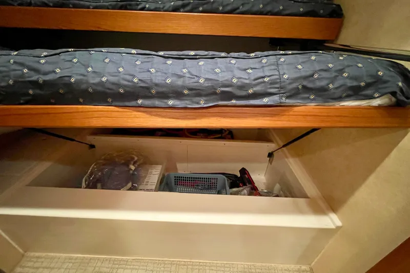 Slide: The Image of Under-bed storage in 2006 Cabo 40 Flybridge yacht, featuring organized compartments and bedding. - 22