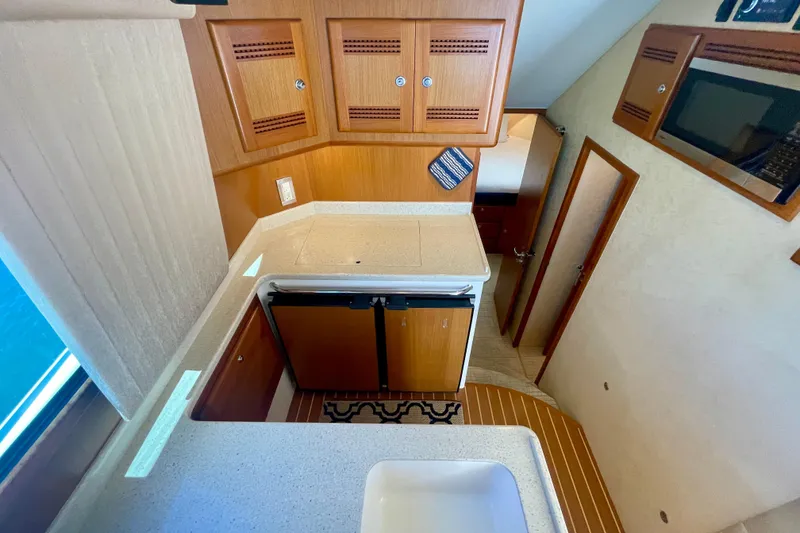 Slide: The Image of Interior view of 2006 Cabo 40 Flybridge yacht kitchen with wooden cabinets and compact design. - 38