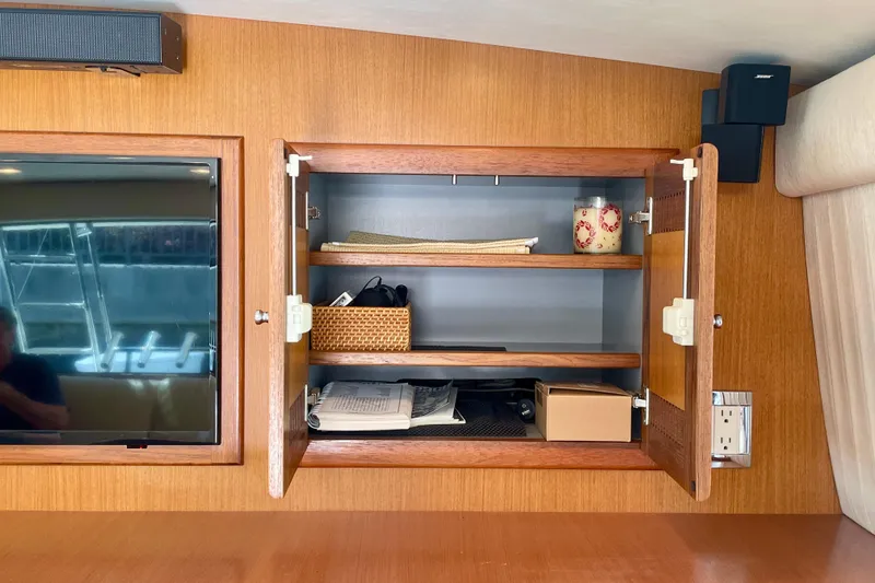 Slide: The Image of Open wooden cabinet on 2006 Cabo 40 Flybridge yacht with shelves and various items. - 49