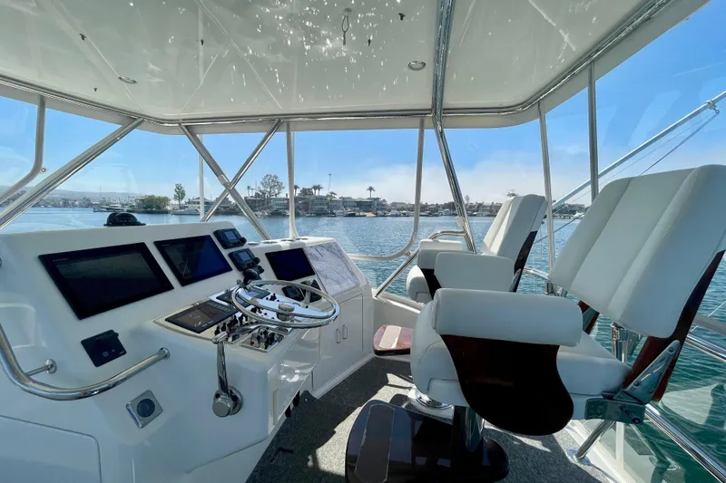 Slide: The Image of Flybridge interior of 2006 Cabo 40, featuring helm controls and seating with marina view. - 56