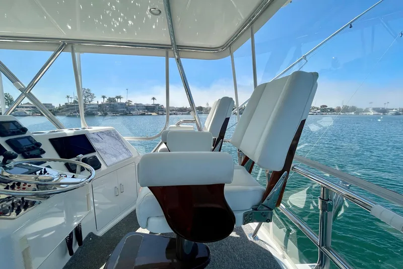 Slide: The Image of Flybridge view of 2006 Cabo 40, featuring helm chairs and navigational equipment, overlooking serene waters. - 57