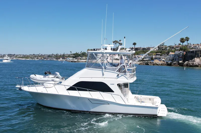 Slide: The Image of 2006 Cabo 40 Flybridge yacht cruising in a scenic coastal area. - 6