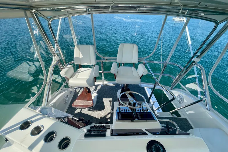 Slide: The Image of Flybridge of 2006 Cabo 40, featuring dual captain chairs and navigational controls, overlooking the ocean. - 64