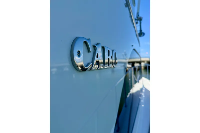 Slide: The Image of Close-up of 2006 Cabo 40 Flybridge yacht nameplate, reflecting sunlight on sleek hull. - 79
