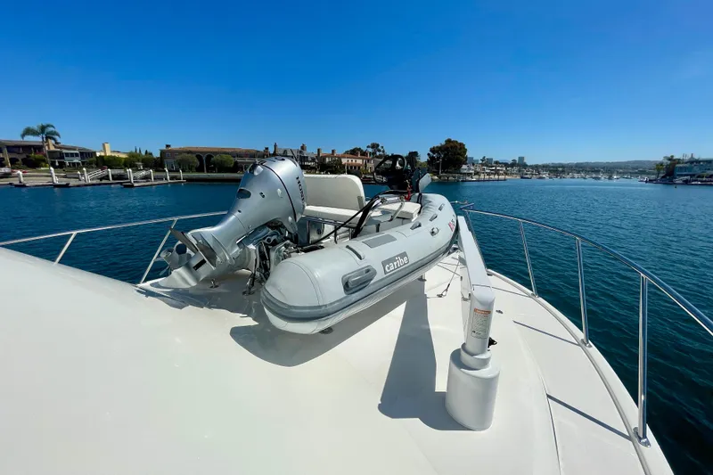 Slide: The Image of 2006 Cabo 40 Flybridge yacht with inflatable boat on deck, docked in scenic marina. - 83