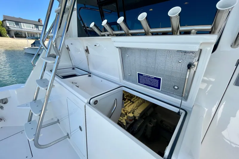 Slide: The Image of 2006 Cabo 40 Flybridge boat with open engine compartment and ladder, docked by waterfront homes. - 95