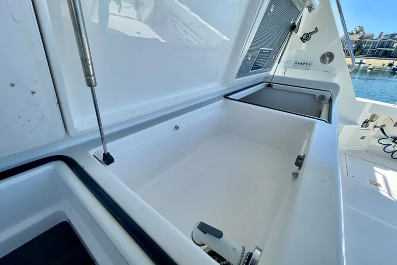 Slide: The Image of Open storage compartment on a 2006 Cabo 40 Flybridge boat, docked by the water. - 98