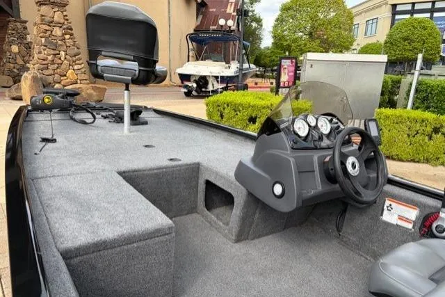 Slide: The Image of 2025 Tracker Pro 170 boat interior with steering console and seating, parked outdoors. - 16