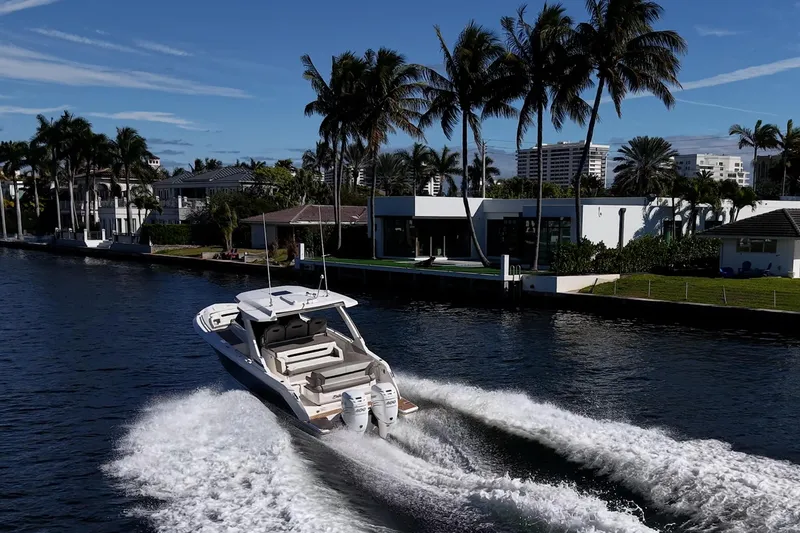 Slide: The Image of 2023 Tiara Sport 34 LS cruising on a scenic waterway with palm trees and luxury homes. - 3