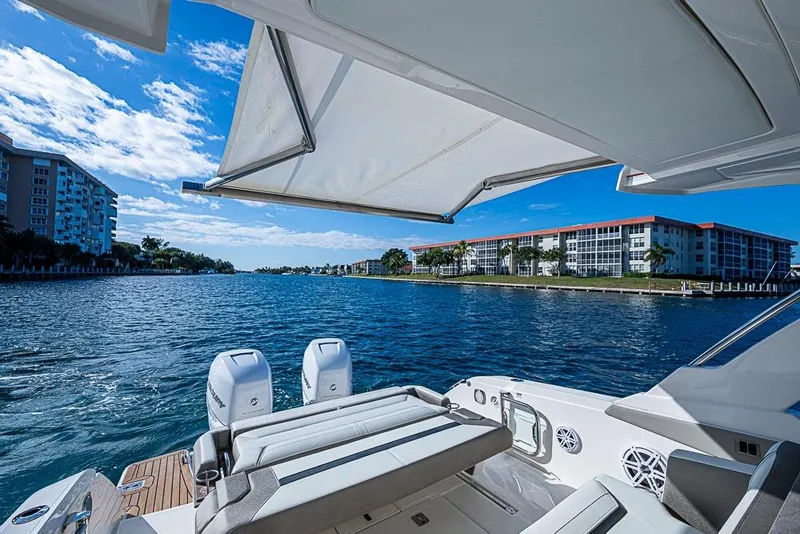 Slide: The Image of 2023 Tiara Sport 34 LS yacht cruising on a sunny waterfront with buildings in view. - 35