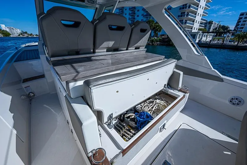 Slide: The Image of 2023 Tiara Sport 34 LS boat with open storage compartment, docked near waterfront buildings. - 39