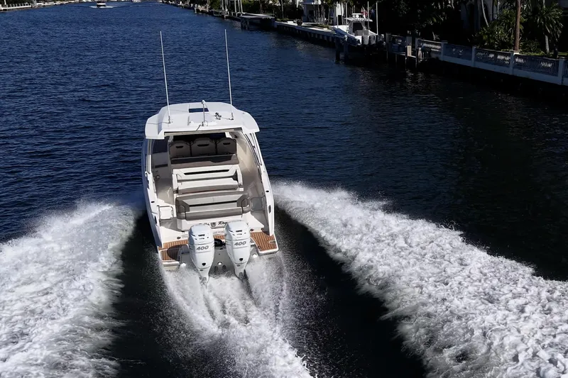 Slide: The Image of 2023 Tiara Sport 34 LS cruising on a scenic waterway, showcasing powerful dual engines. - 5