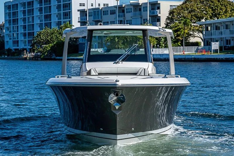 Slide: The Image of 2023 Tiara Sport 34 LS boat cruising on a sunny waterfront near modern buildings. - 55