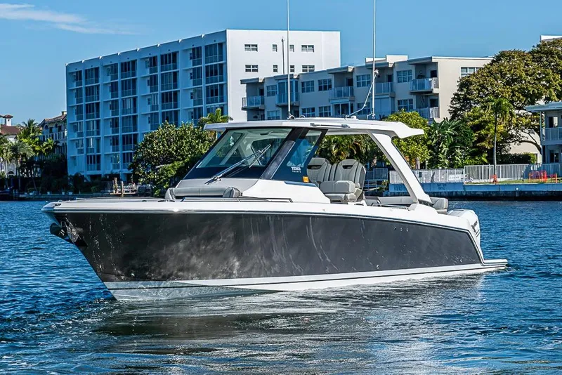 Slide: The Image of 2023 Tiara Sport 34 LS boat cruising near waterfront buildings. - 57