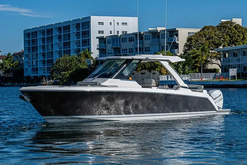 Slide: The Image of 2023 Tiara Sport 34 LS boat cruising on a sunny waterfront near modern buildings. - 58