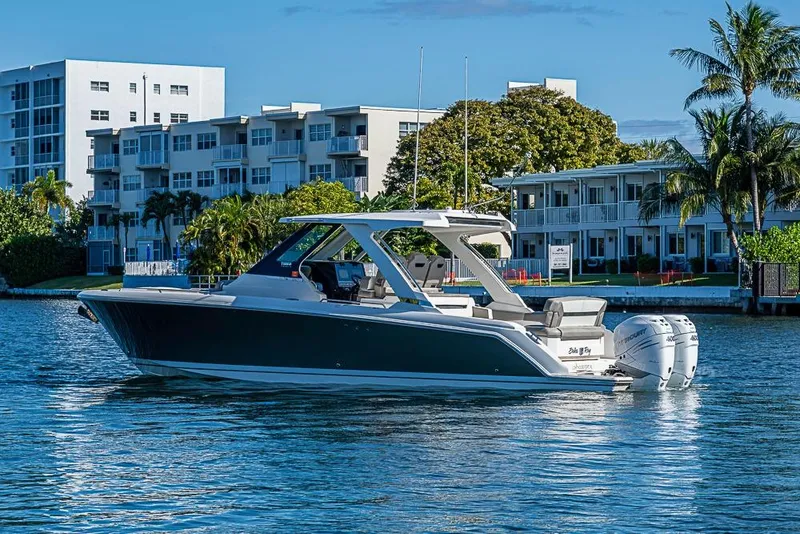 Slide: The Image of 2023 Tiara Sport 34 LS boat on water near modern buildings and palm trees. - 61