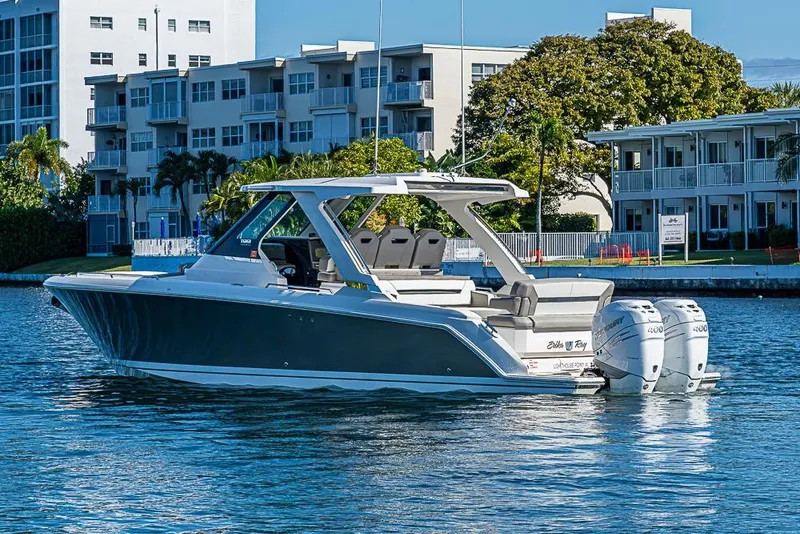 Slide: The Image of 2023 Tiara Sport 34 LS boat on water, with modern buildings in the background. - 62