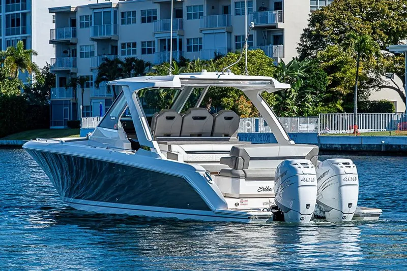 Slide: The Image of 2023 Tiara Sport 34 LS boat with dual Mercury engines on a sunny waterfront. - 63