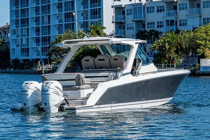 Slide: The Image of 2023 Tiara Sport 34 LS boat with dual Mercury engines on a sunny waterfront. - 65