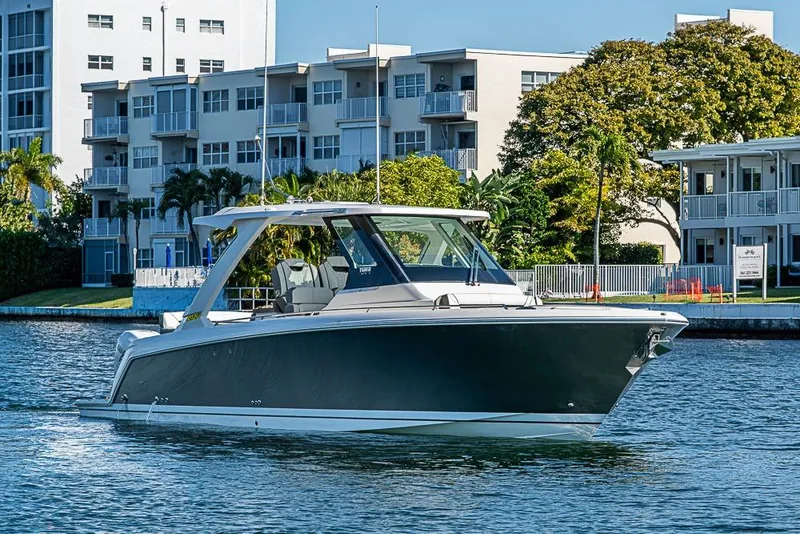 Slide: The Image of 2023 Tiara Sport 34 LS boat cruising near waterfront buildings. - 68