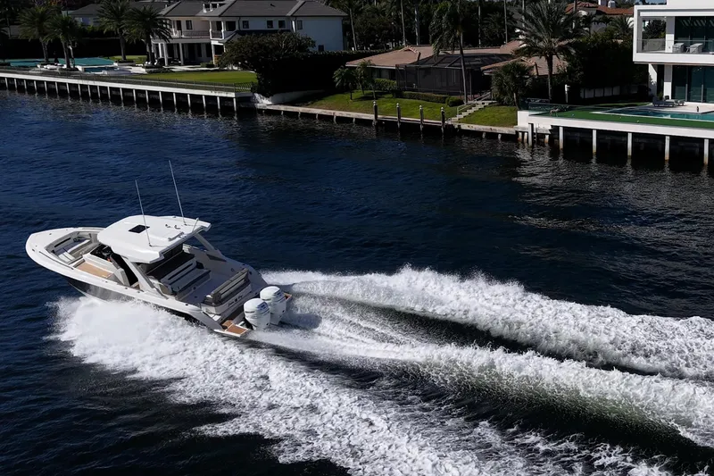 Slide: The Image of 2023 Tiara Sport 34 LS cruising on a scenic waterfront near luxury homes. - 9