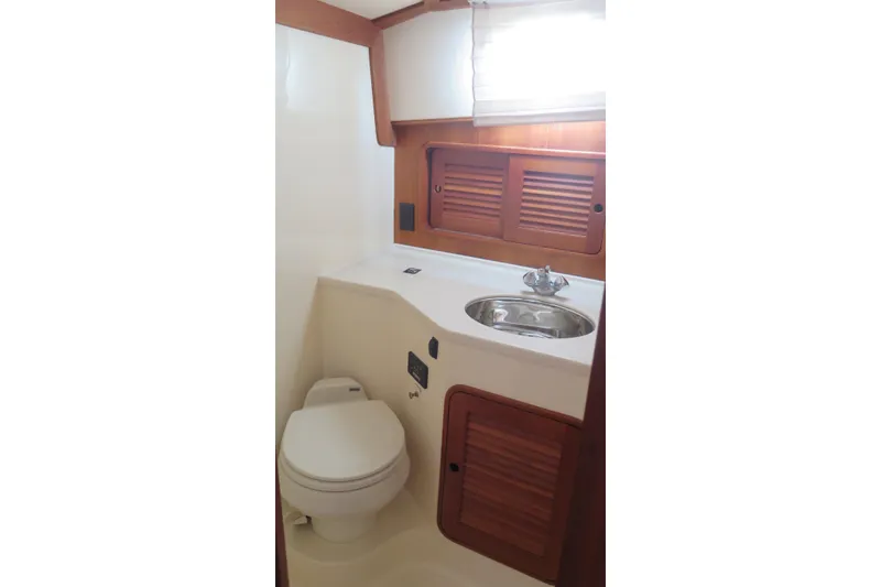 Slide: The Image of Hinckley Talaria 40 yacht bathroom, featuring a toilet, sink, and wooden cabinetry, 2007 model. - 26