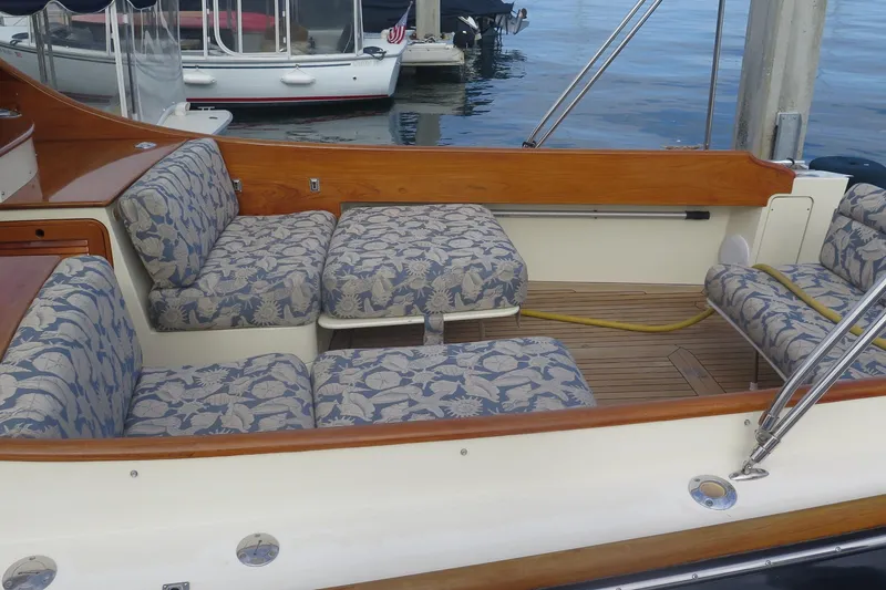 Slide: The Image of Hinckley Talaria 40 boat interior with patterned seating, wooden accents, and docked boats in background. - 31