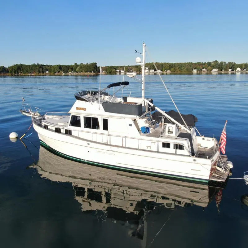 The Image of 1989 Grand Banks 46 Classic yacht on calm water, with American flag and clear sky. - 0