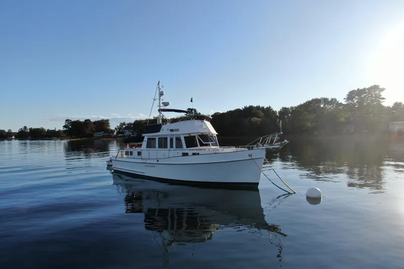 Slide: The Image of 1989 Grand Banks 46 Classic yacht on calm water, surrounded by trees. - 10