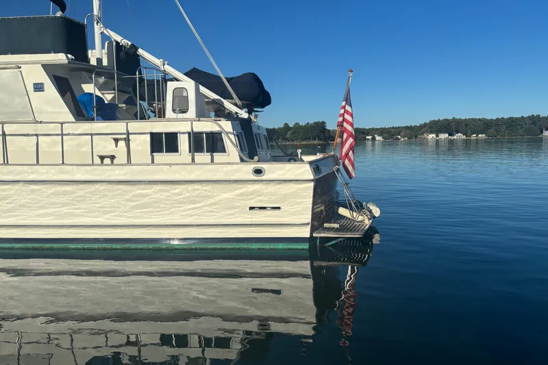 Slide: The Image of 1989 Grand Banks 46 Classic yacht on calm water with American flag. - 19