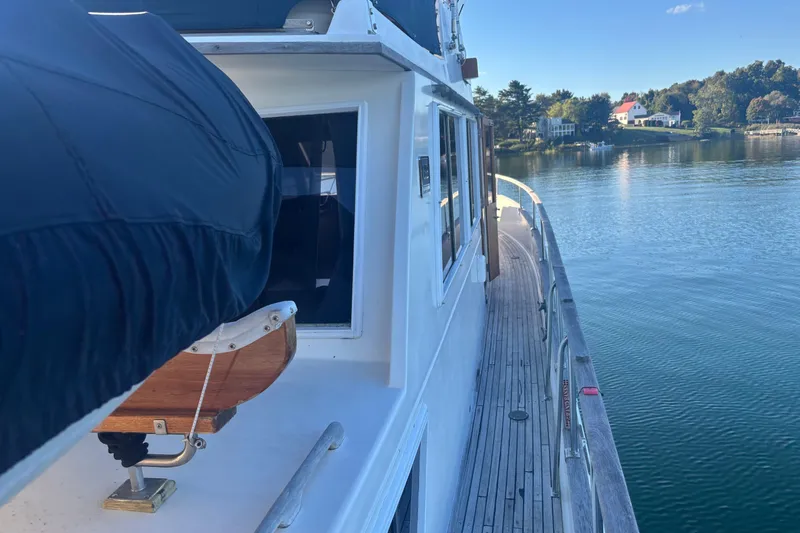 Slide: The Image of 1989 Grand Banks 46 Classic yacht on serene water, showcasing deck and scenic shoreline. - 26