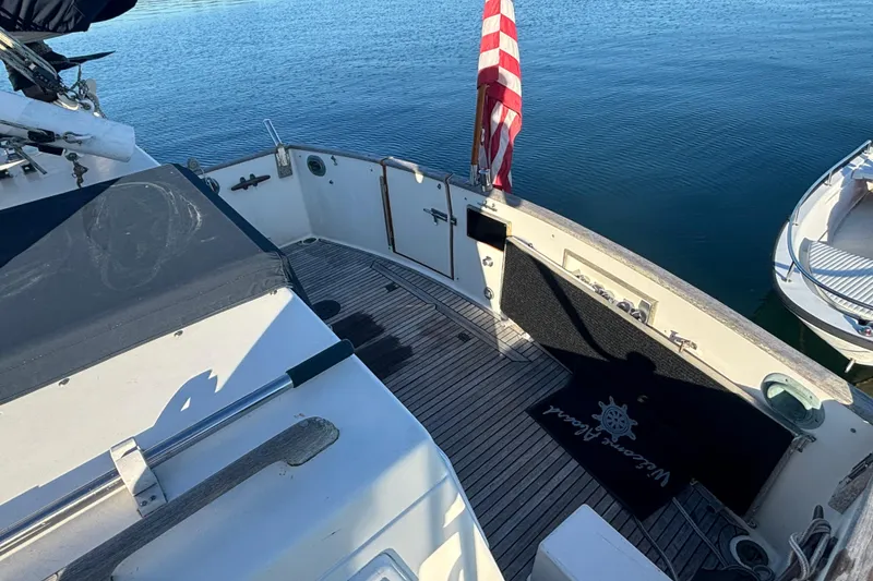 Slide: The Image of 1989 Grand Banks 46 Classic yacht deck with American flag, docked on calm water. - 42
