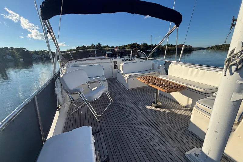Slide: The Image of 1989 Grand Banks 46 Classic yacht deck with seating and table, overlooking calm waters. - 46
