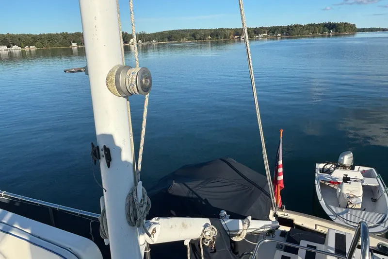 Slide: The Image of 1989 Grand Banks 46 Classic yacht on serene lake with American flag and small boat. - 57