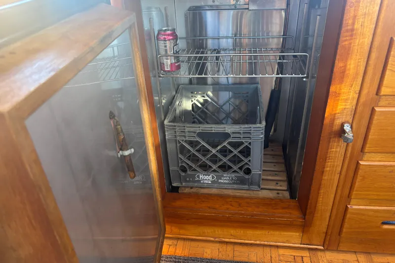 Slide: The Image of Open wooden cabinet on 1989 Grand Banks 46 Classic boat, showing storage with crate and soda can. - 86