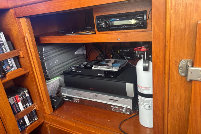 Slide: The Image of Entertainment system in a 1989 Grand Banks 46 Classic yacht with DVDs and fire extinguisher. - 97