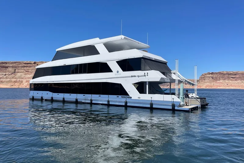 The Image of Luxurious 2022 Adonia Layin' Low houseboat on serene lake with scenic cliffs. - 0