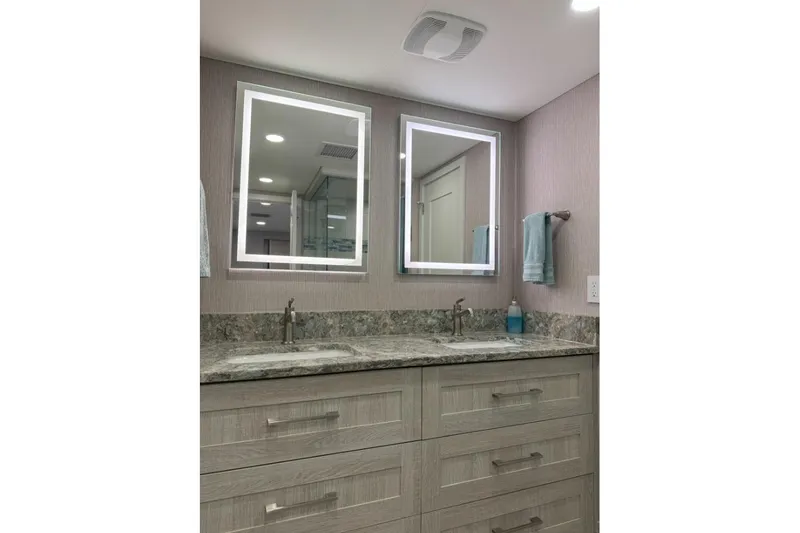 Slide: The Image of Modern bathroom with dual sinks, illuminated mirrors, and sleek cabinetry in Adonia Layin' Low 2022 model. - 10