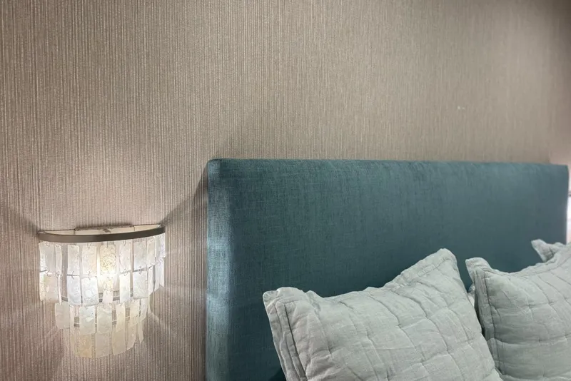 Slide: The Image of Elegant bedroom with teal headboard, textured wall, and decorative wall sconce. Adonia Layin' Low 2022. - 14