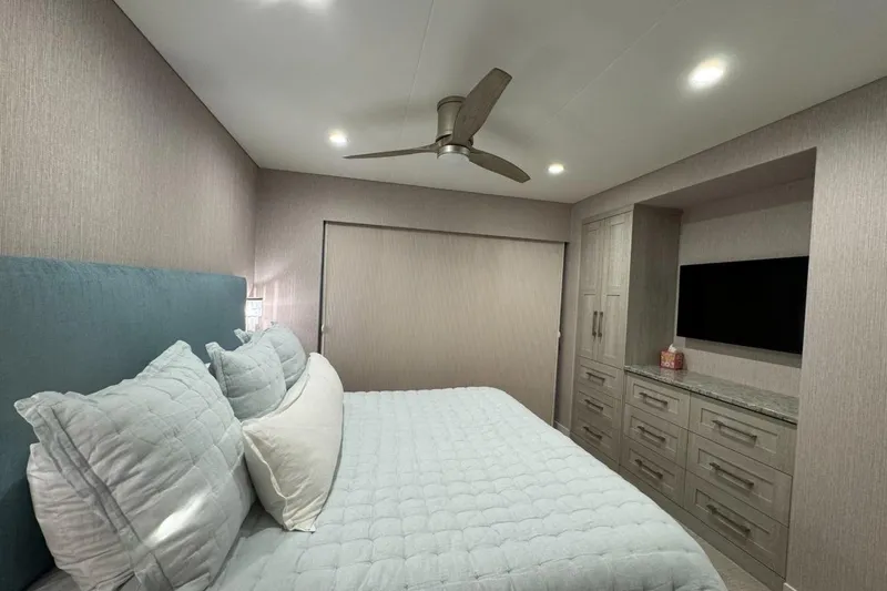 Slide: The Image of Modern bedroom in 2022 Adonia Layin' Low RV with cozy bed, ceiling fan, and TV. - 15