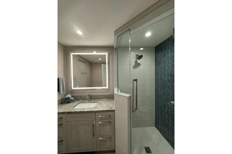 Slide: The Image of Modern bathroom with granite countertop, illuminated mirror, and glass shower in 2022 Adonia Layin' Low. - 20