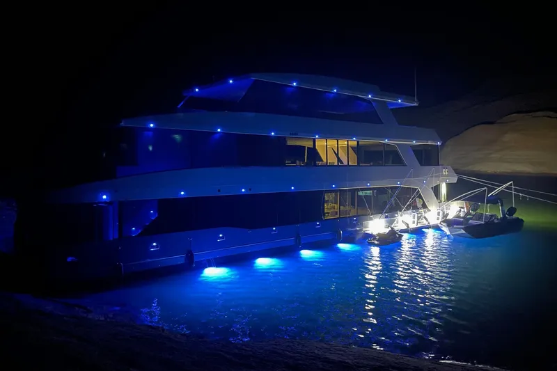 Slide: The Image of Luxurious 2022 Adonia Layin' Low houseboat illuminated with blue lights at night. - 4